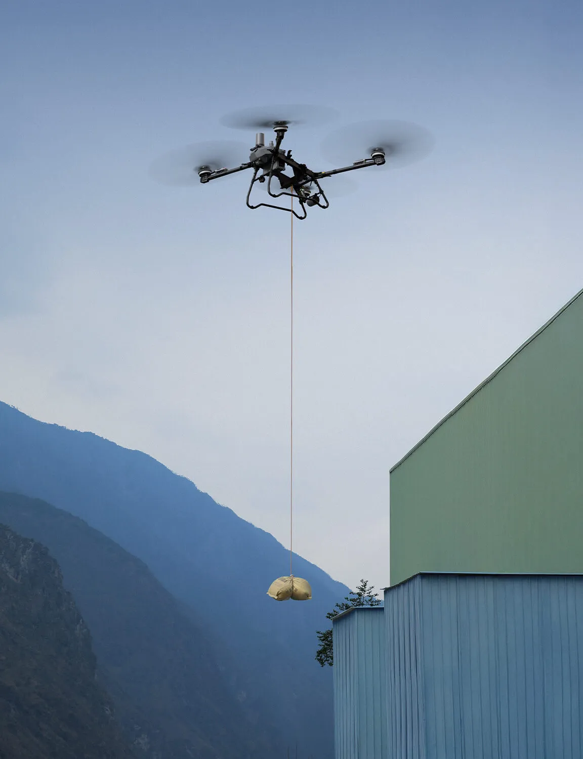 Dron transportando un saco de material junto a una nave