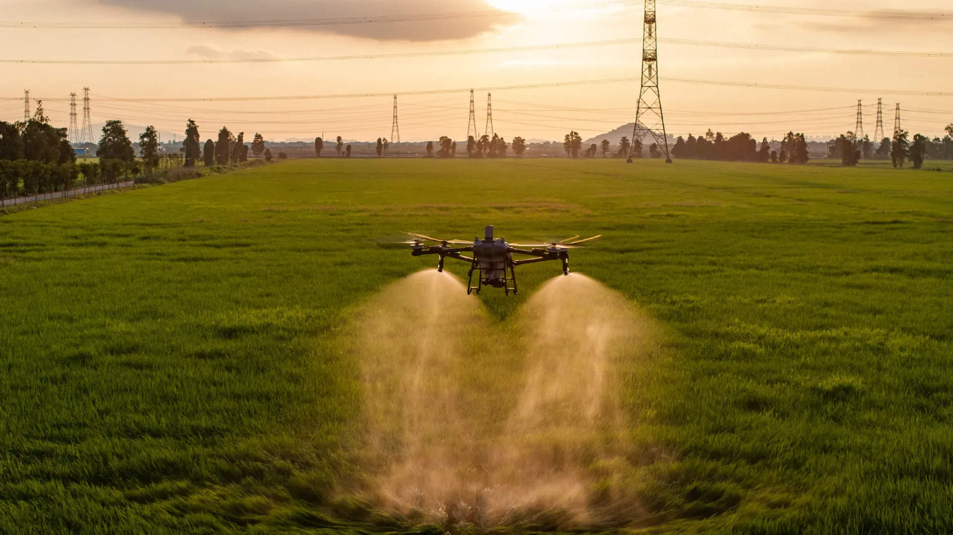 Dron aplicando un tratamiento sobre un campo al atardecer